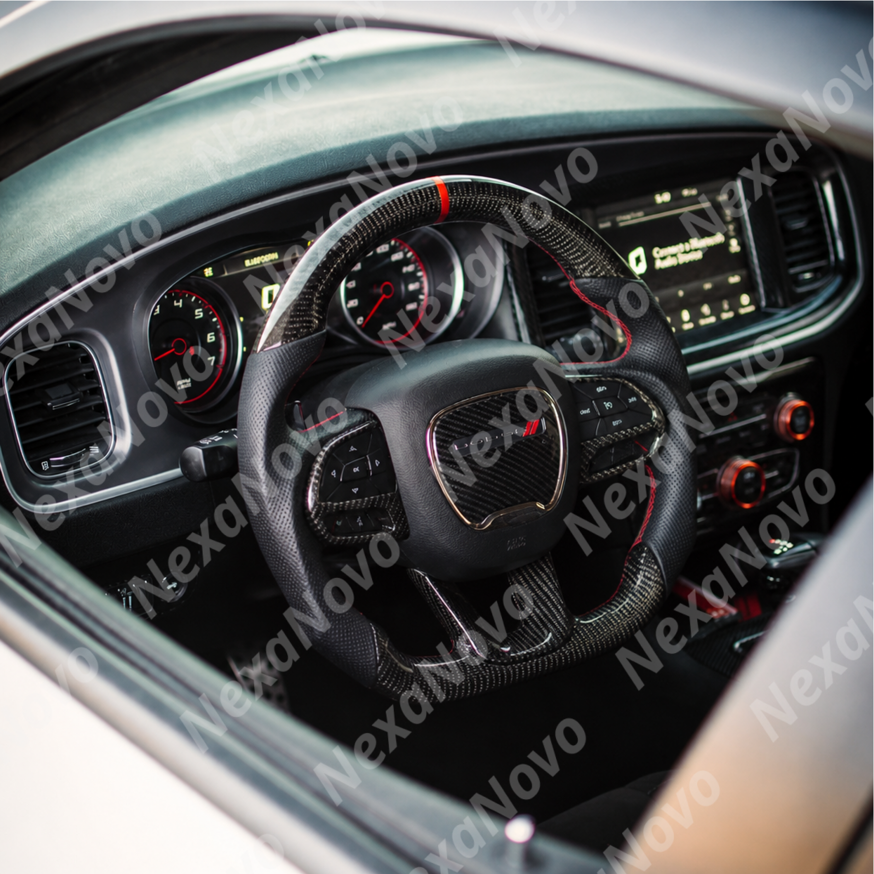 Driver seat view showing the carbon fiber steering wheel framing the retro-inspired Dodge gauge cluster