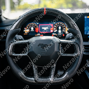 Driver seat view showing the carbon fiber steering wheel framing the dual curved digital display screens