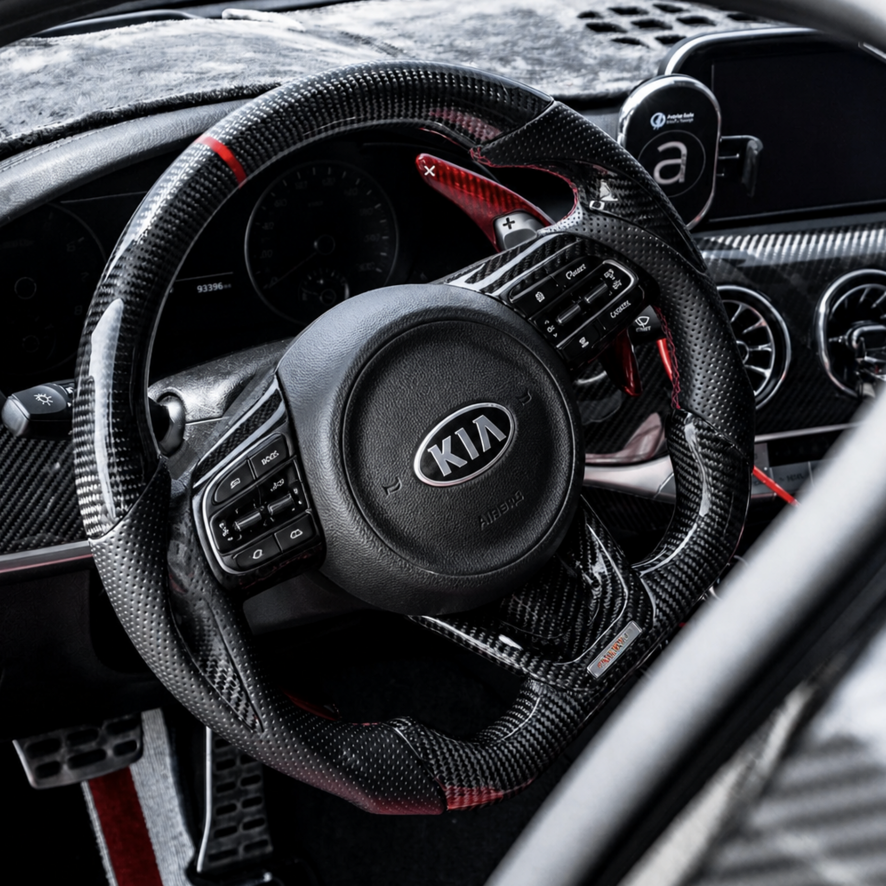 Driver seat view showing the carbon fiber steering wheel framing the digital cluster and turbine air vents