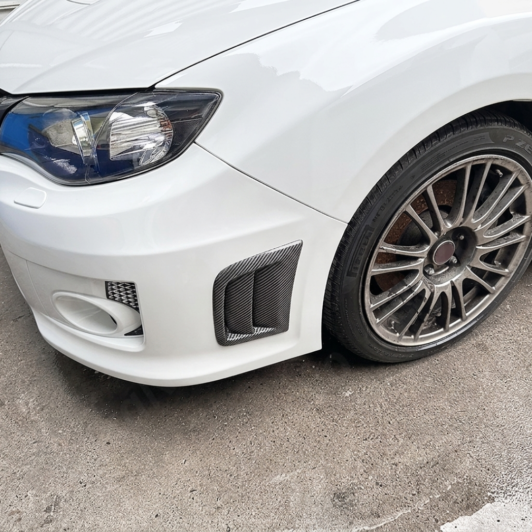 Sporty carbon fiber print vents providing a race-inspired look on a Satin White Pearl Subaru STI